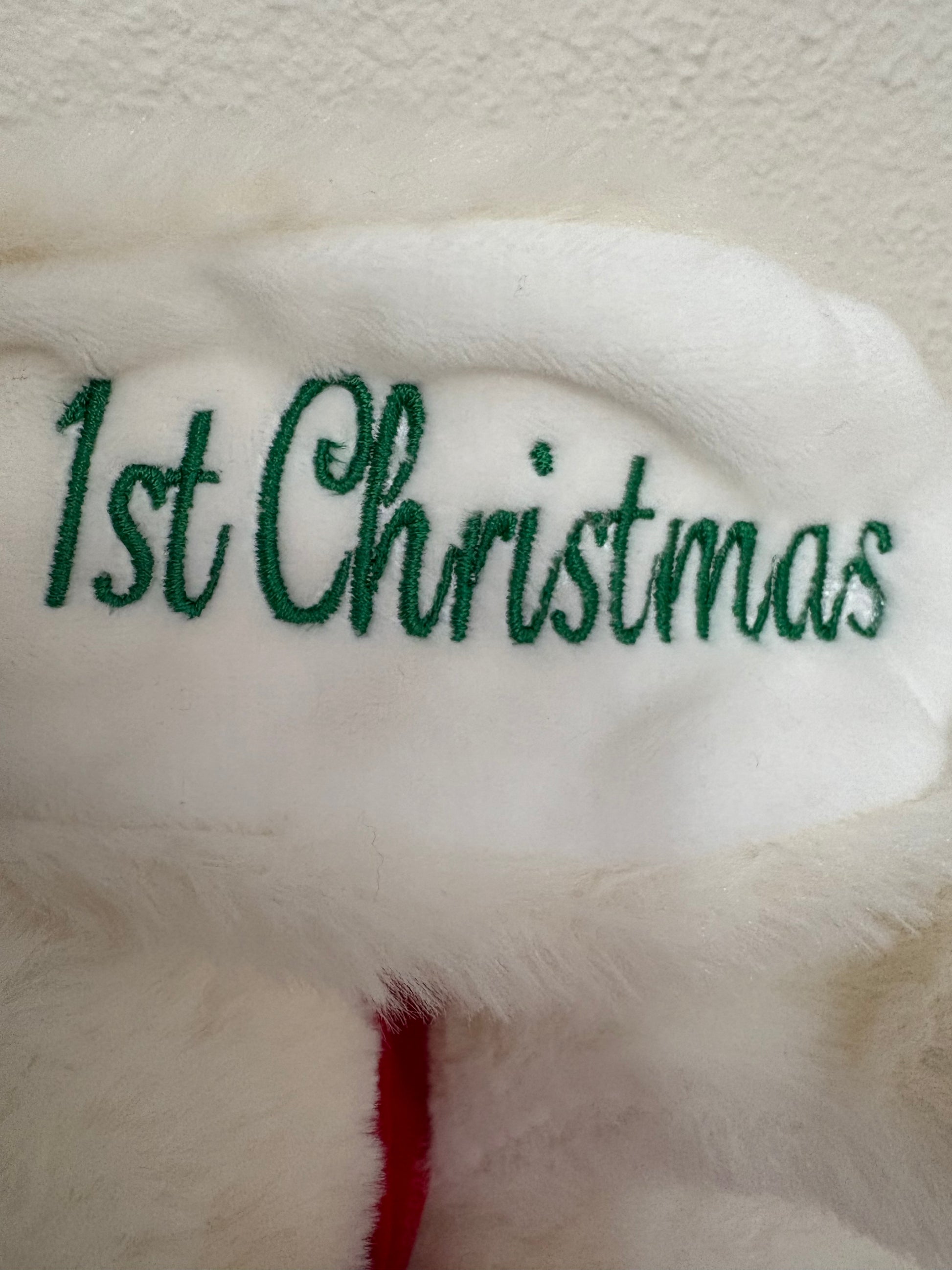 White teddy bear with '1st Christmas' embroidered in green on a white background