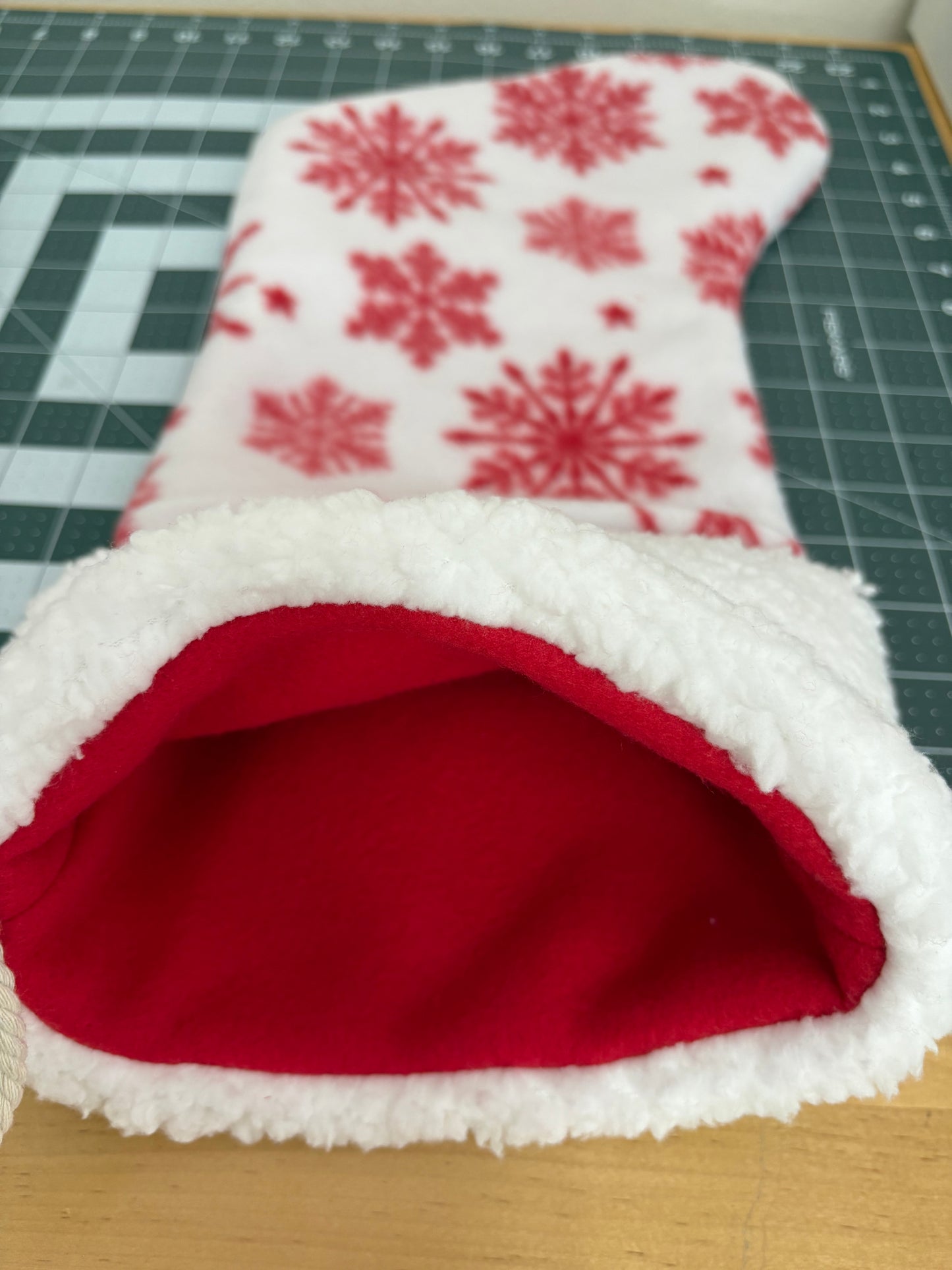 Red fabric with white snowflake pattern on a cutting mat