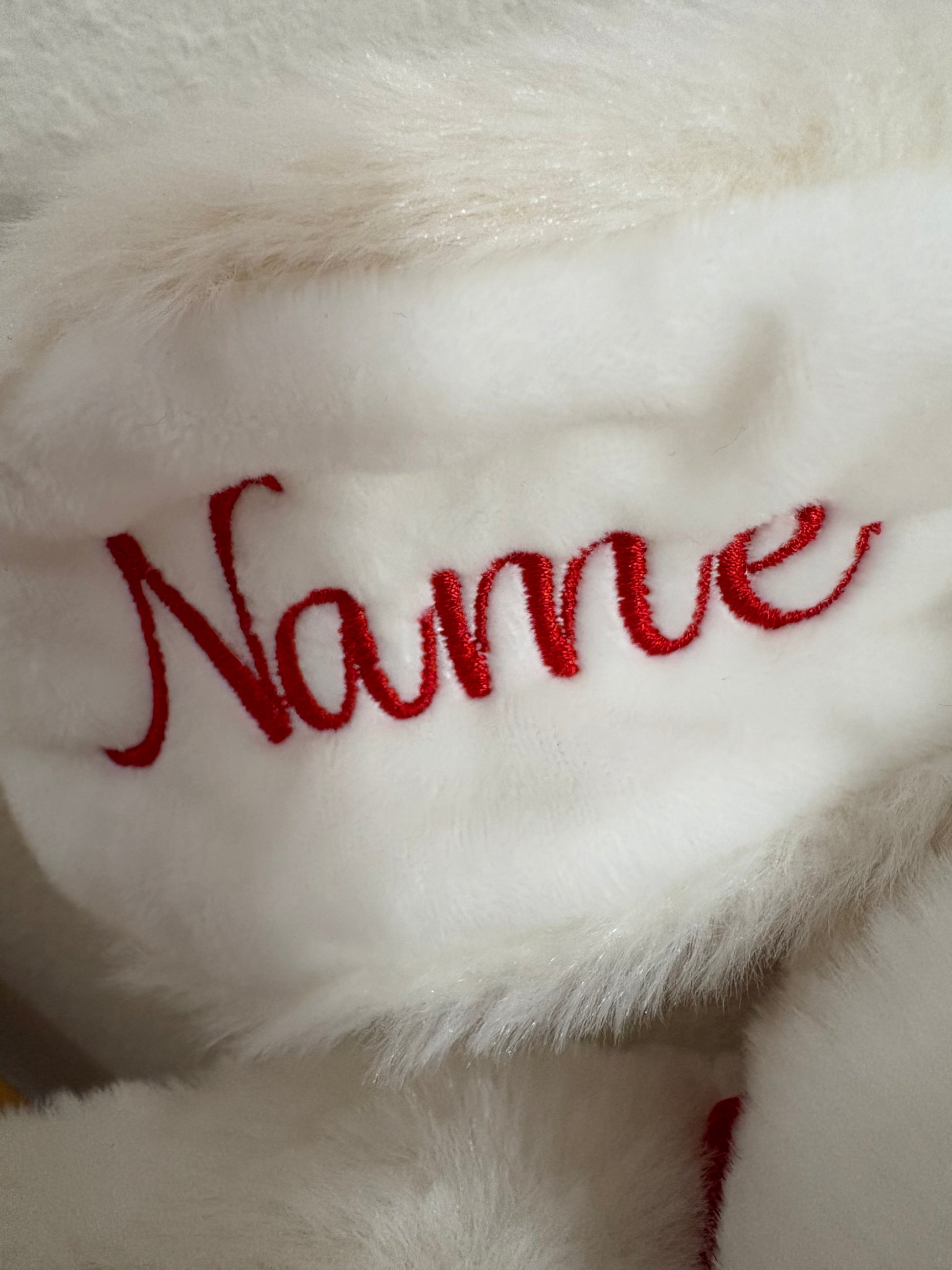 White plush toy with red embroidered name on a soft white background